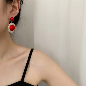 Élégantes boucles d'oreilles rouges géométriques avec strass brillants portées par mannequin