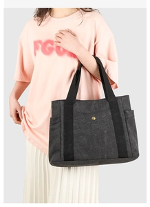 Vue détaillée du sac cabas en toile gris foncé avec sangle noire renforcée et bouton pression