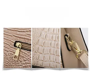Detail view of beige embossed crocodile texture and gold metal zipper on the shoulder bag