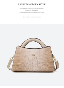 Detail of crocodile embossed texture on beige handbag with gold V-shaped metal logo