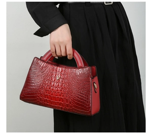 Close-up of deep red crocodile texture handbag featuring a gold V-shaped metal hardware