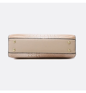 Detail of beige crocodile embossed handbag bottom with four protective gold metal studs