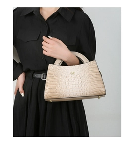 Detail of apricot crocodile pattern handbag with gold V-shaped logo and sturdy handles