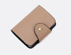 Detail of nude pink pebble leather small wallet with gold snap button and black trim