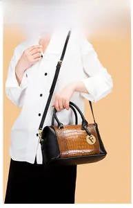 Detail of embossed crocodile pattern on brown and black tote bag with gold pendant