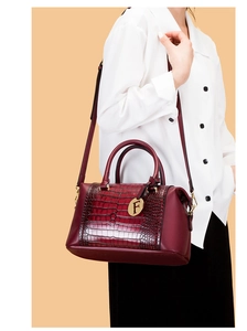 Detail of burgundy crocodile embossed handbag featuring a golden letter F charm