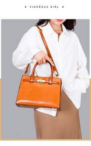 Detail of crocodile-embossed orange leather tote with gold metal twist lock and handle
