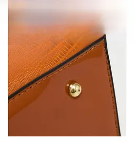 Detail of gold metal feet on embossed leather handbag base for wear resistance