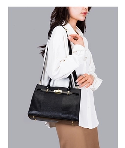 Detail of black embossed leather handbag with gold metal lock and protective base studs
