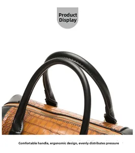 Detail of ergonomic decompression handle on brown crocodile leather handbag with gold zipper