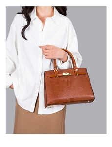 Detail of brown lizard-patterned handbag with golden metal hardware and sturdy handles