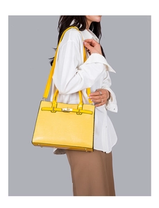 Detailed side view of yellow lizard-patterned handbag on model with metal clasp and strap
