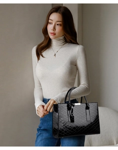 Detail einer schwarzen Lackleder-Handtasche mit Rautenprägung und silbernen Akzenten