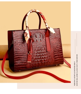 Dettaglio borsa rossa con trama a coccodrillo e sciarpa di seta decorativa sul manico