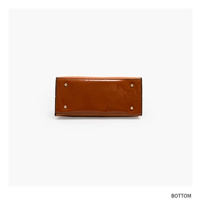 Detail of the brown patent leather handbag base featuring four protective gold metal studs