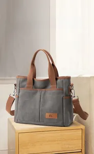 Gros plan du sac fourre-tout en toile grise avec anses brunes et grandes poches