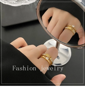 Detail of gold double-layer zircon ring on finger with mirror reflection view