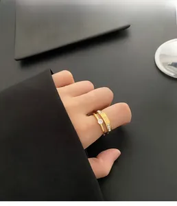 Close-up of gold zircon rings set worn by model against a high-contrast dark background