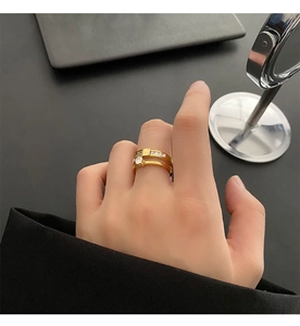 Detail of gold double-layered zircon ring featuring letter engraving and a round main stone