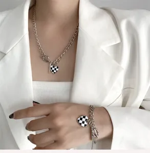 Détail des pendentifs cœur en damier sur colliers et bracelets en métal épais