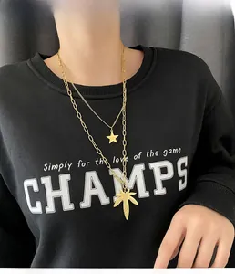 Detail of layered gold titanium steel necklaces with star and maple leaf pendants