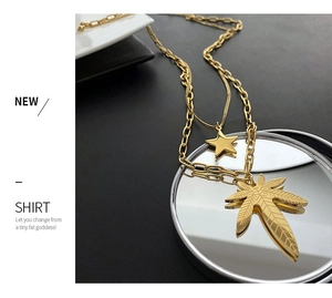 Close-up of double-layered gold stainless steel necklace with maple leaf and star pendants