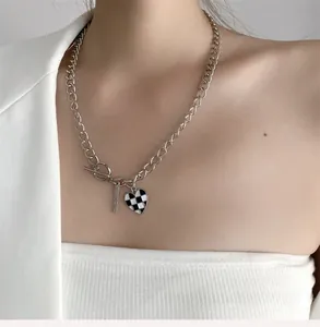 Détail du pendentif cœur en damier sur un collier à boucle OT argentée pour femme