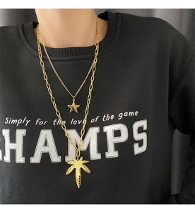 Macro detail of gold-plated double layer necklace with maple leaf and star pendants