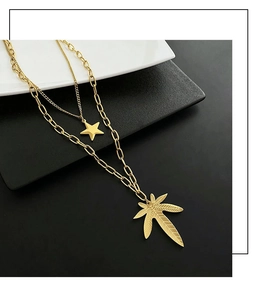 Close-up of gold layered titanium necklace with star and textured leaf pendants