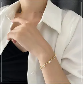 Détail d'un élégant bracelet ondulé doré avec zircons sur le poignet d'une femme