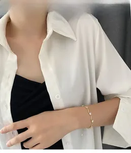 Gros plan d'un bracelet doré en forme de vague avec zircons blancs sur le poignet
