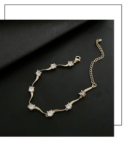 Détail du bracelet chaîne épines dorées avec zircons ronds sur fond noir élégant