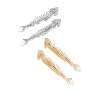 Detailed close-up of gold and silver fishbone earrings with pearls on white background