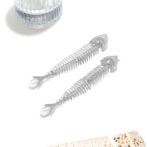 Detail of silver fishbone earring featuring sparkling crystal eye and white pearl drop