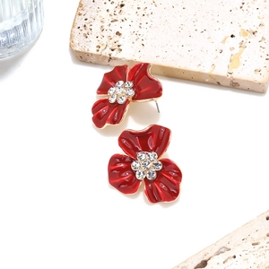 Détail des boucles d'oreilles fleur en émail rouge avec des centres en strass