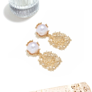 Detailed close-up of vintage gold lion head earrings with white pearl inlay on stone