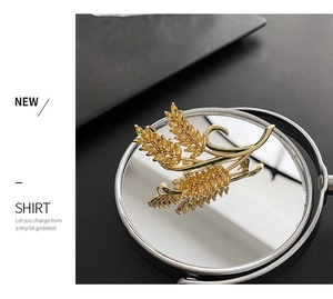 Macro detail of golden wheat brooch with sparkling yellow zircon on a mirror