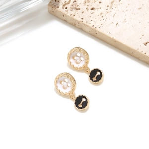Detail of creative black and white button drop earrings with gold metal frame accents