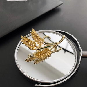 Elegant gold wheat brooch with yellow zircon crystals shown on a mirror surface