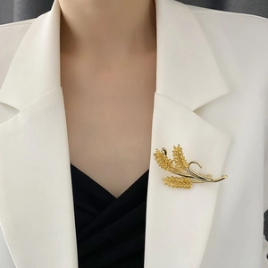 Elegant gold wheat ear brooch with zircon accents on a white blazer lapel