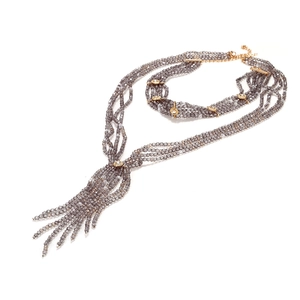 Detail of multi-strand grey beaded necklace featuring golden accents and tassel pendant