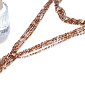 Detailed close-up of bohemian layered brown beaded necklace with gold rhinestone discs