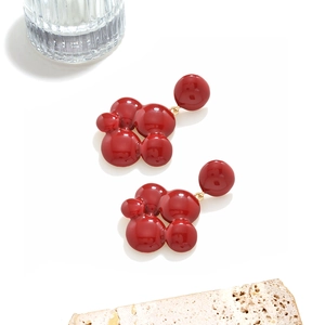 Vue détaillée de boucles d'oreilles émaillées rouge foncé avec accents dorés