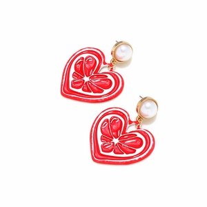 Détail de boucles d'oreilles cœur rouge avec texture d'orange et perle nacrée
