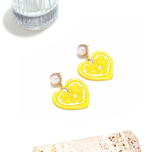 Gros plan détaillé de boucles d'oreilles cœur citron avec perle sur fond de pierre