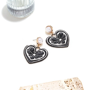 Détails de boucles d'oreilles cœur avec motif émail agrumes et accents de perles blanches