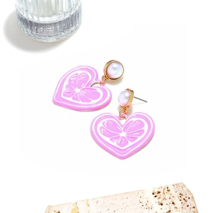 Gros plan de boucles d'oreilles cœur rose avec perle sur support en pierre
