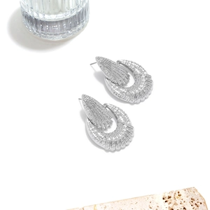 Detailed view of silver hollow earrings with geometric texture on travertine stone