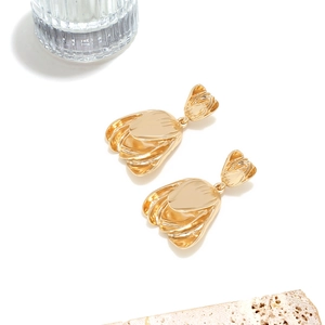 Detailed view of gold lantern flower earrings with metallic textures on a stone pedestal
