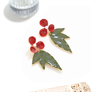 Detail of enamel flower earrings with red petals, green spotted leaf and pearl accents